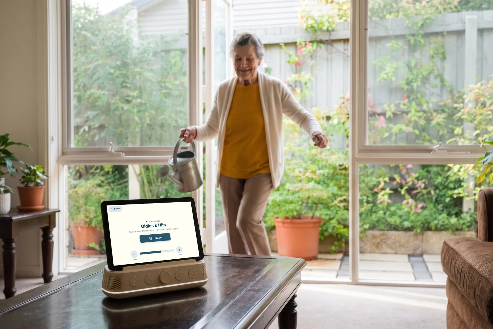 An older woman waters her plants in the conservatory while Amara plays music on the table.